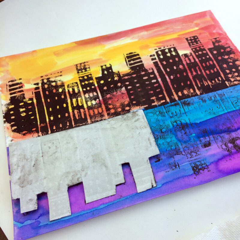 A brightly colored skyline has prints of black buildings on it.